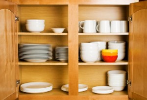 Dishes neatly stacked in wood cabinets.